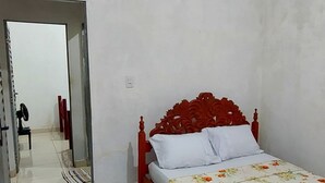 Un dormitorio con cama, un espejo, una puerta y un pasillo que conduce a otra habitación.