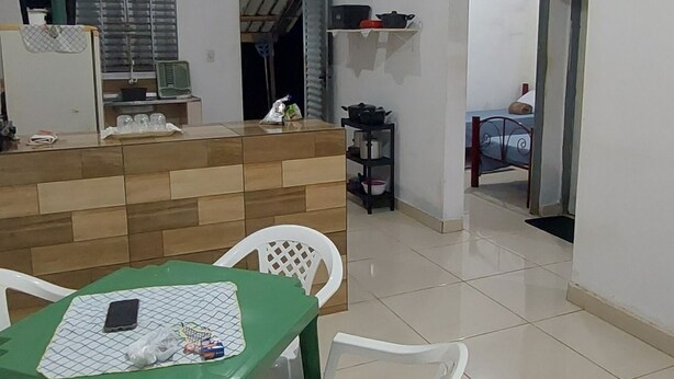 Un comedor con una mesa verde, sillas blancas y una cocina al fondo.