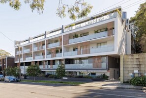 A modern multi-story residential building with balconies, a flat roof, and a concrete facade.