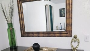 A dark wooden dresser with drawers, a mirror, and decorative items including a vase with branches, a tray with spherical objects, and a metallic sculpture. - WALKING DISTANCE FROM HARD ROCK STADIUM
1-bedroom apartment Miami Gardens (Miami Gardens)