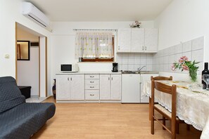 A compact kitchen with white cabinets, a microwave, a coffee maker, and a dining area with a table and chairs. - Apartment 2436/208293 (Istria - Valbandon), 1500m from the beach (Valbandon)