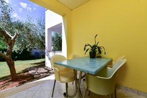 A patio with a table and chairs, a potted plant, and a view of a garden. - Apartment 2436/208293 (Istria - Valbandon), 1500m from the beach (Valbandon)