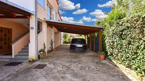 Ein Haus mit überdachter Auffahrt, einem in der Mitte geparkten Auto und einer Treppe zum Eingang.