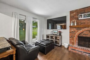Ein Wohnzimmer mit Kamin, Ledersofa und Esstisch.