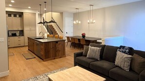 A modern kitchen with wooden cabinets, a central island, and pendant lighting. - Elevated game-day getaway with rooftop hot tub (St. George)
