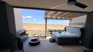 A modern outdoor balcony with a hot tub, seating, and a view of the desert landscape. - Elevated game-day getaway with rooftop hot tub (St. George)
