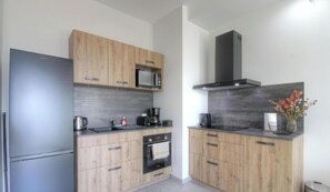Eine moderne Küche mit Kühlschrank, Mikrowelle, Kaffeemaschine, Backofen und Holzschränken.