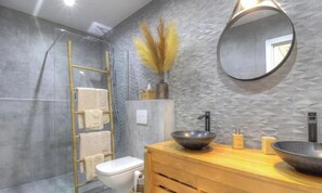 Ein modernes Badezimmer mit Duschkabine aus Glas, Waschtisch aus Holz und einem großen Spiegel.