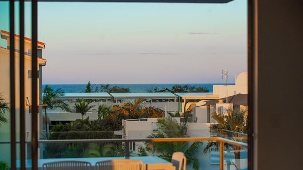Un balcon avec vue sur la mer et les palmiers.