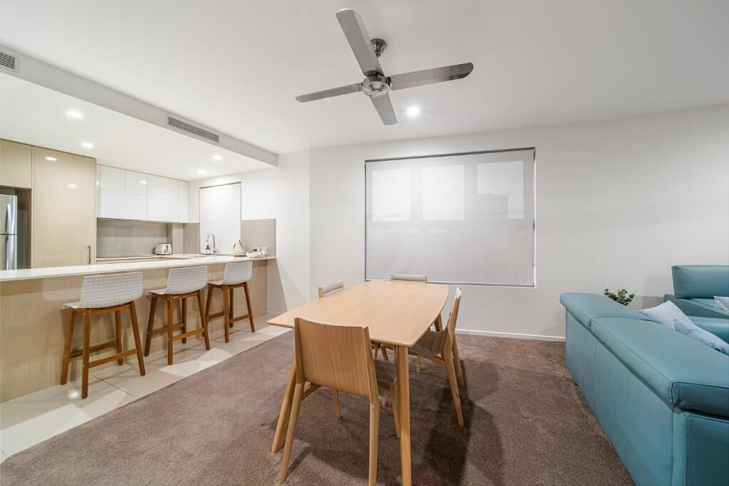 Une cuisine moderne avec un coin repas, un ventilateur de plafond et une grande fenêtre.