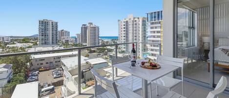 A balcony with a table set for two, a bottle of wine, and a fruit platter.