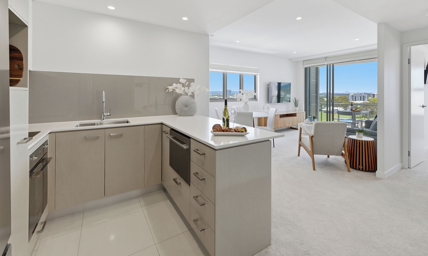 A modern kitchen with a central island, a dining area with a view, and a large window.