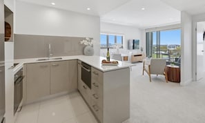 A modern kitchen with a large island, a dining area with a view, and a balcony with a chair.