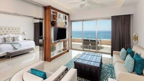 A modern hotel room with a bed, a TV, a sofa, a coffee table, and a balcony with a view of the sea. - Luxurious All-inclusive 2BR Suite at Garza Blanca Cancun  Thanksgiving Week 2026 (Cancún)