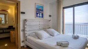 Quarto de hotel com cama, banheiro e varanda com vista.