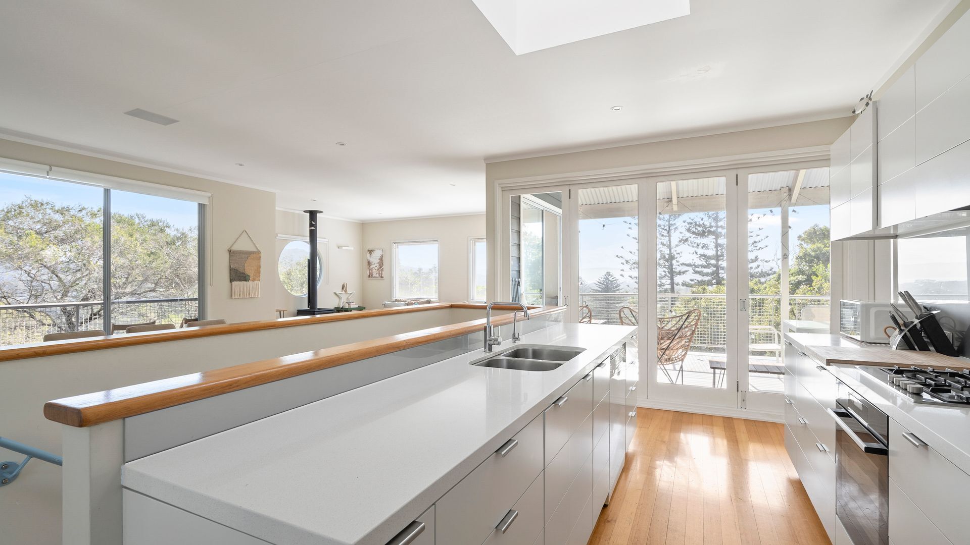 A modern kitchen with a large island, sliding glass doors to a balcony, and a view of the outdoors.