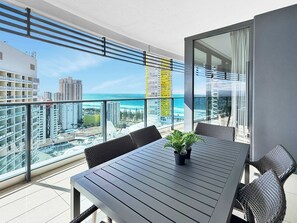Een balkon met een tafel, stoelen, een bloempot en uitzicht op de stad.