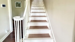 A staircase with white railings and brown mats at each step, leading to an upper floor. - Wren House by Kirk Murphy Hospitality (Moultrie)