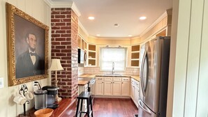 A kitchen with a wooden floor, a refrigerator, a sink, and a window with blinds. - Wren House by Kirk Murphy Hospitality (Moultrie)
