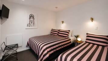 A bedroom with two beds, a radiator, a TV, and a wall-mounted light fixture.