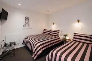 Ein Schlafzimmer mit zwei Betten, einem Heizkörper, einem Fernseher und einer Wandleuchte.