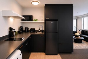 A modern kitchen with a black refrigerator, a microwave, a coffee maker, and a sink. - Central CBD | Walk to Te Pae, Stadium + Parking (Christchurch)