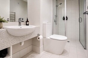 Een moderne badkamer met een witte wastafel, toilet en douche.