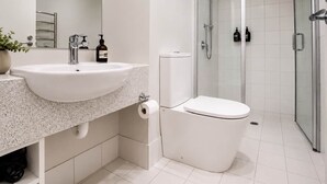 A modern bathroom with a white sink, toilet, and shower.