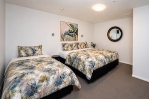 Ein Schlafzimmer mit zwei Betten, einem runden Spiegel und einem Bild an der Wand.