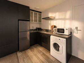 Eine kompakte Küche mit integriertem Kühlschrank, einer Mikrowelle und einer Waschmaschine.