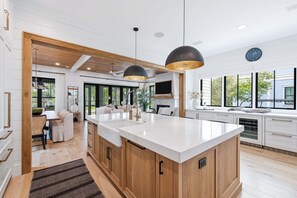 A modern kitchen with a large island, wooden cabinets, and pendant lighting. - NEW! WaterColor Phase 1 Location! LSV/Golf Cart & 4 Bikes Included! (Santa Rosa Beach)
