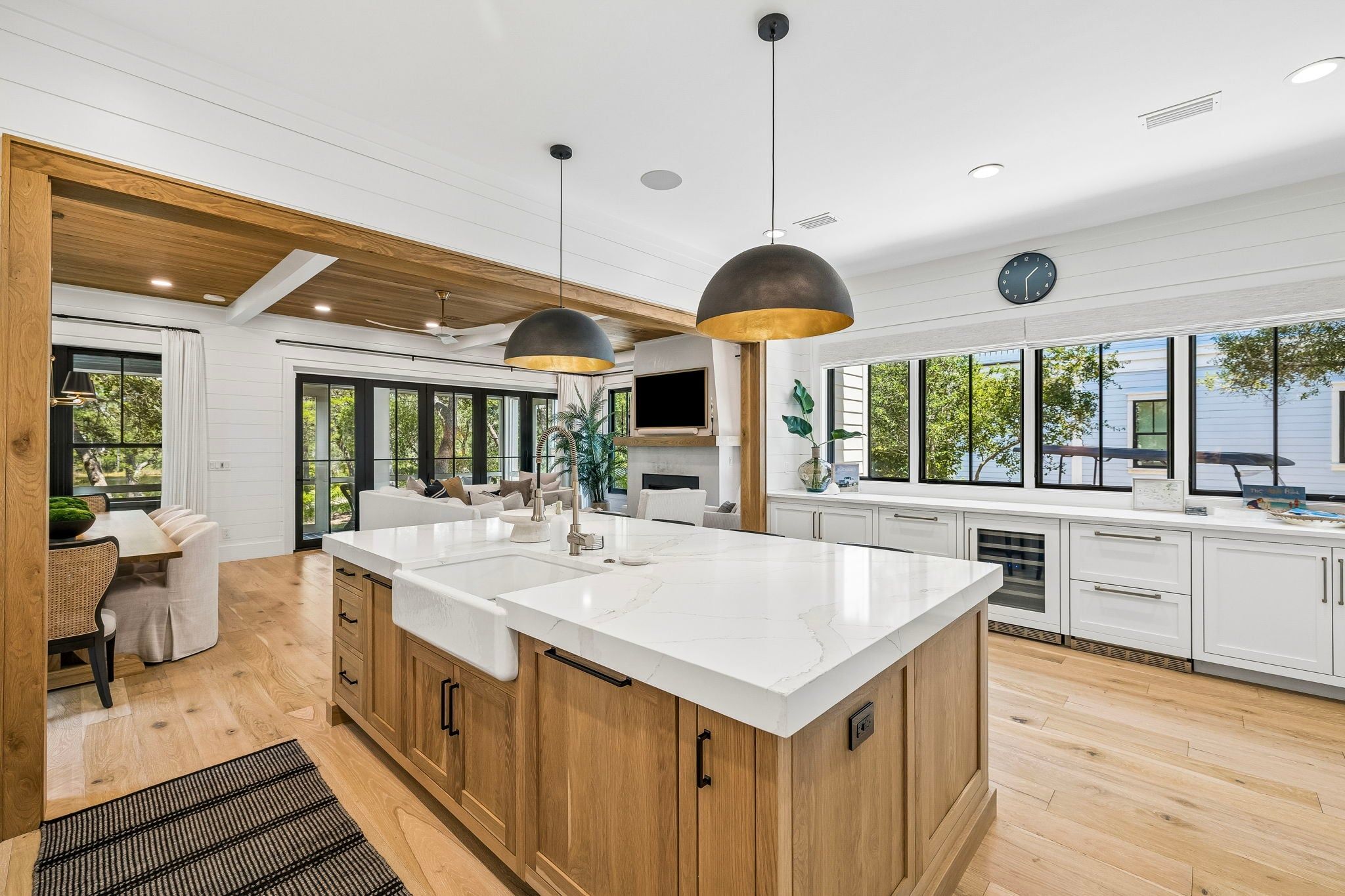 A modern kitchen with a large island, wooden cabinets, and a dining area with a view.