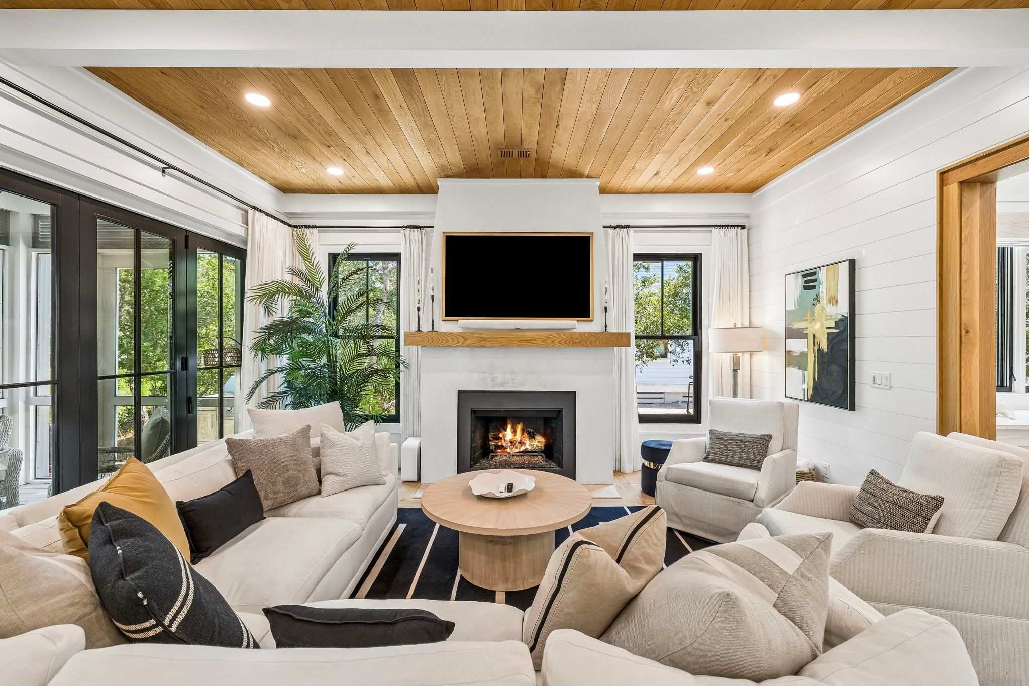 A modern living room with a fireplace, comfortable seating, and a large TV mounted above it.