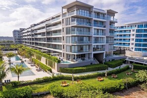 Ein mehrstöckiges Hotel mit Balkonen, einem Swimmingpool und gepflegten Gärten.