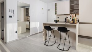 Eine moderne Küche mit Barbereich, zwei schwarzen Barhocker und einer Arbeitsplatte mit diversen Gegenständen.