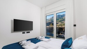 Ein Hotelzimmer mit Bett, Flachbildfernseher, Fenster mit Bergblick und Balkon.