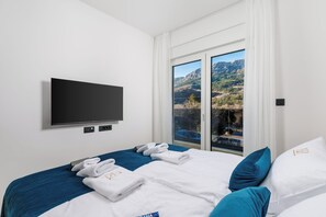 Ein Hotelzimmer mit Bett, Flachbildfernseher, Fenster mit Bergblick und Balkon.