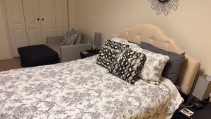 A bedroom with a bed, a nightstand, a lamp, a chair, and a wardrobe. - Welcoming 2-bedroom basement apartment with AC in vibrant Atlanta (Atlanta)