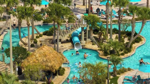 Een resort met meerdere zwembaden, palmbomen en een glijbaan.