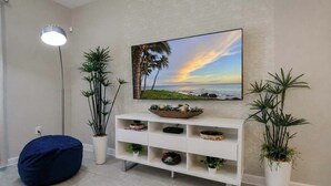 Een woonkamer met een witte console tafel, een blauwe pluchen zitbal en twee potplanten.