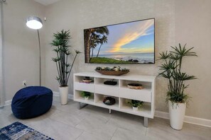 A living room with a white console table, a blue bean bag, and two potted plants. - Luxury Disney Retreat: Pvt Pool + Resort Access (Kissimmee)