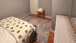 A bedroom with a bed, a wooden nightstand, a door, and a mirror. - Elite room stay (Bridgeport)
