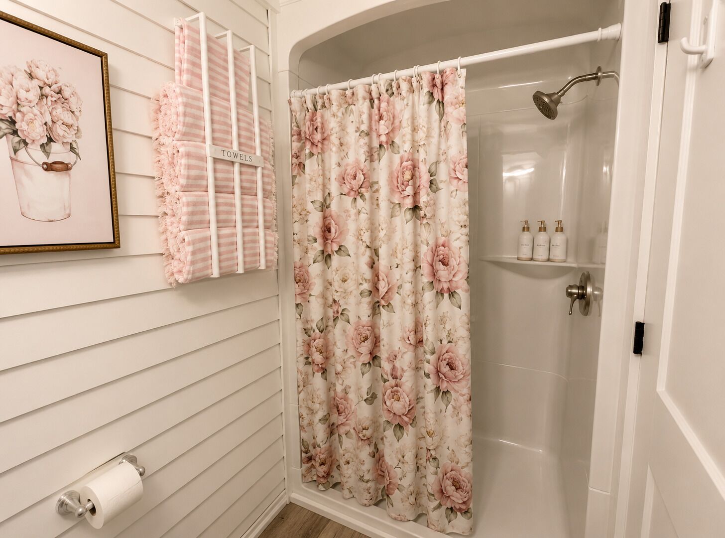 Une salle de bain équipée d’un rideau de douche, d’un porte-serviettes et d’un support à papier toilette.