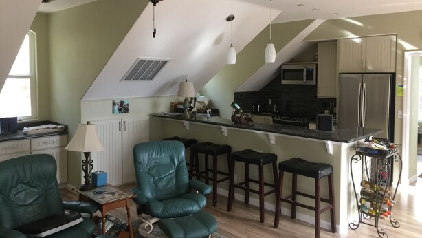Een moderne keuken met een plafondventilator, barstoelen en een wijnrek.