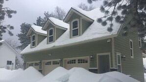 Een huis met twee verdiepingen, een sneeuwbedekte kap en een garage.