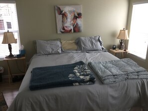 A neatly made bed with pillows, a blanket, and a painting of a cow on the wall. - New secluded apt nestled among the tall pines in charming Running Springs (Running Springs)