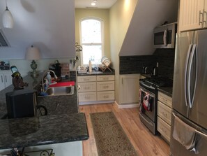 A kitchen with a granite countertop, stainless steel appliances, a window with a view, and wooden flooring. - New secluded apt nestled among the tall pines in charming Running Springs (Running Springs)