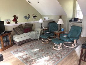 A cozy living room with a sofa, two green armchairs, a coffee table, a television, and a bookshelf. - New secluded apt nestled among the tall pines in charming Running Springs (Running Springs)