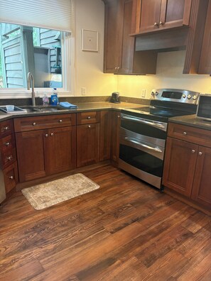 A kitchen with wooden cabinets, a stainless steel oven, and a granite countertop. - Golf View Condo - Pool Steps Away -  Beach Access (Hilton Head Island)