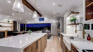 A modern kitchen with a large island, wooden cabinets, and a pendant light. - South Bay Sweet Spot: Walk to Hermosa & MB Piers 5 bdrm home 2 Blocks from Beach (Hermosa Beach)